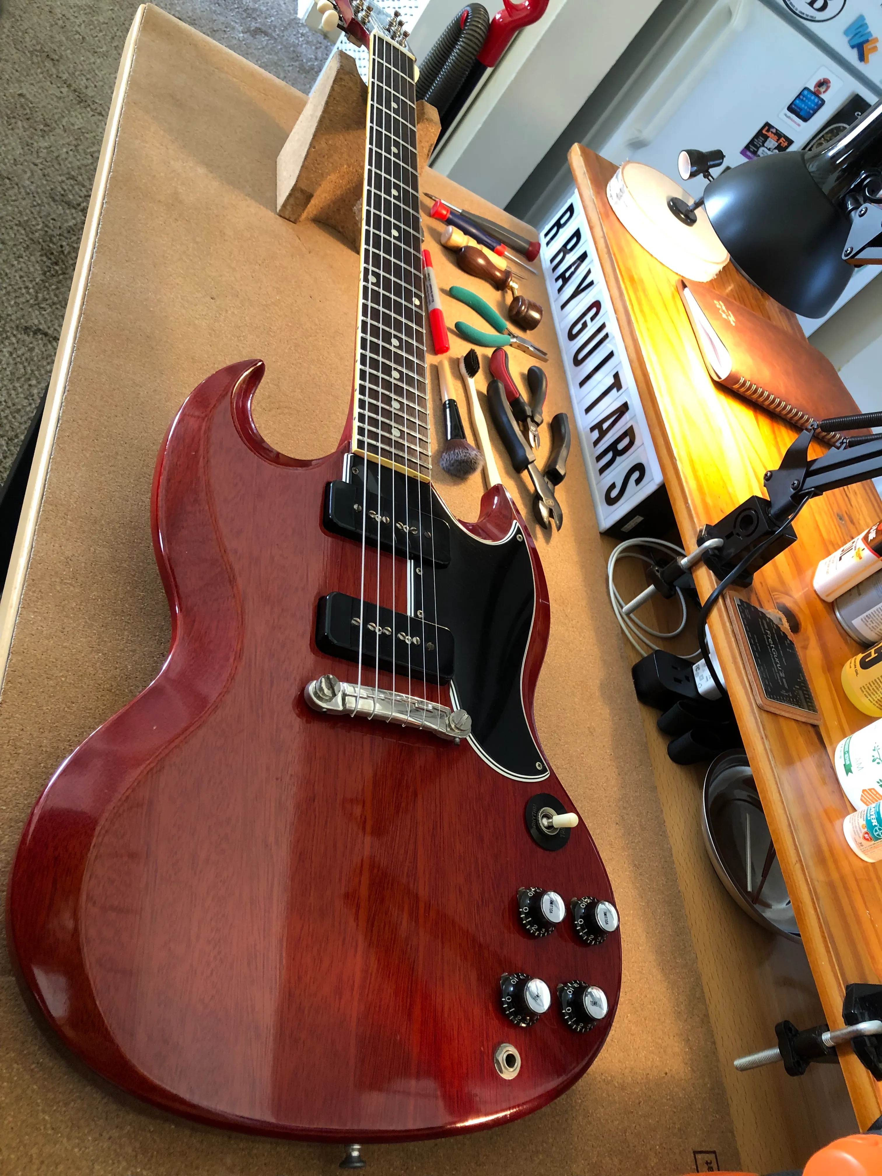 Cherry red SG electric guitar on the R. Ray Guitars workbench
